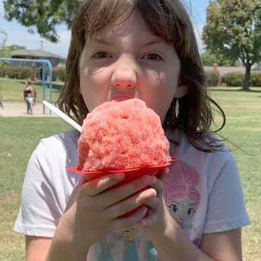 Girl eating a big red shave ice at a festival